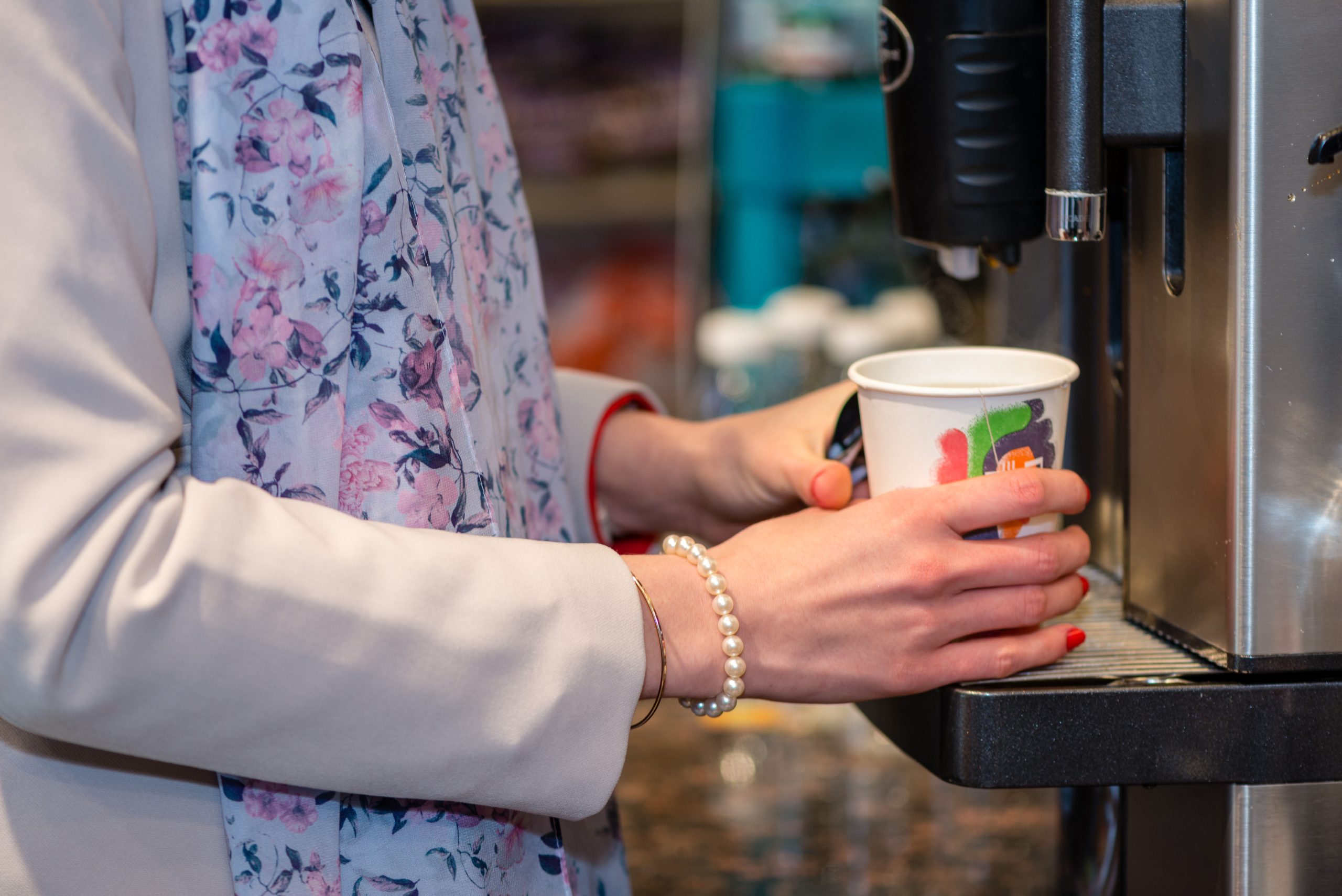 Lady holding cup by a coffee machine in a convenience story powered by Pentair Foodservice Water & Ice Solutions Background