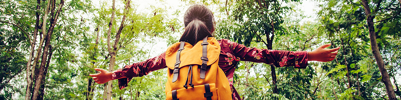 Woman wearing orange backpack with arms wide in nature for Pentair About Us Page