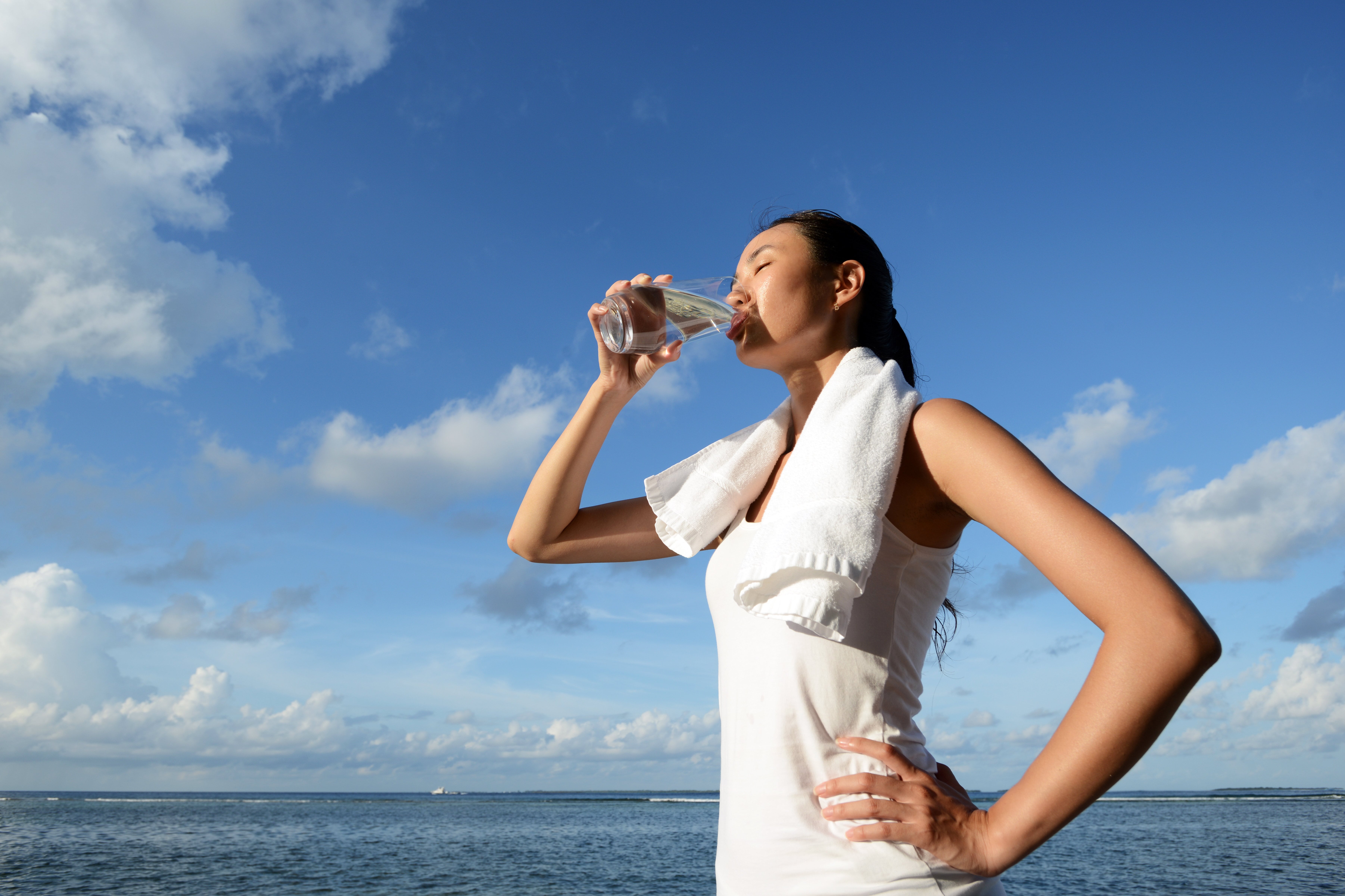 Woman drinking water a glass of water by the sea powered by Pentair