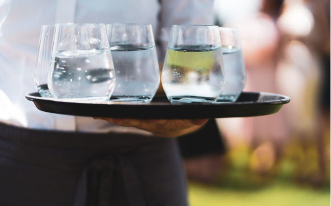 Waiter carrying glasses of ice water powered by Pentair Water Filtration Solutions for Foodservice