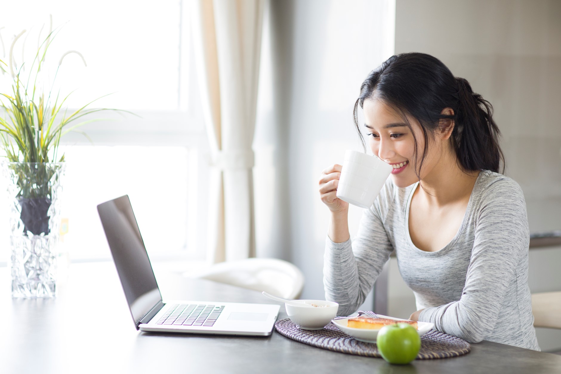 Woman drinking water powered by Pentair Water Filter Solutions while working on-a-laptop