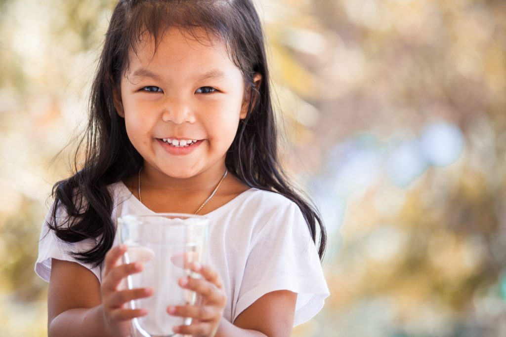 Cute asian little girl holding glass of fresh water for Pentair Home Water Filtration Solutions