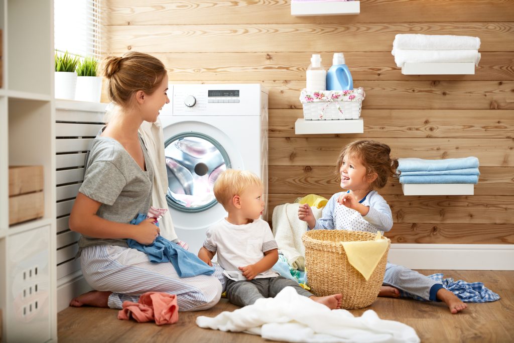 Happy family mother and children in laundry load washing machine powered by Pentair - Pool, Water Treatment, and Flow Technologies