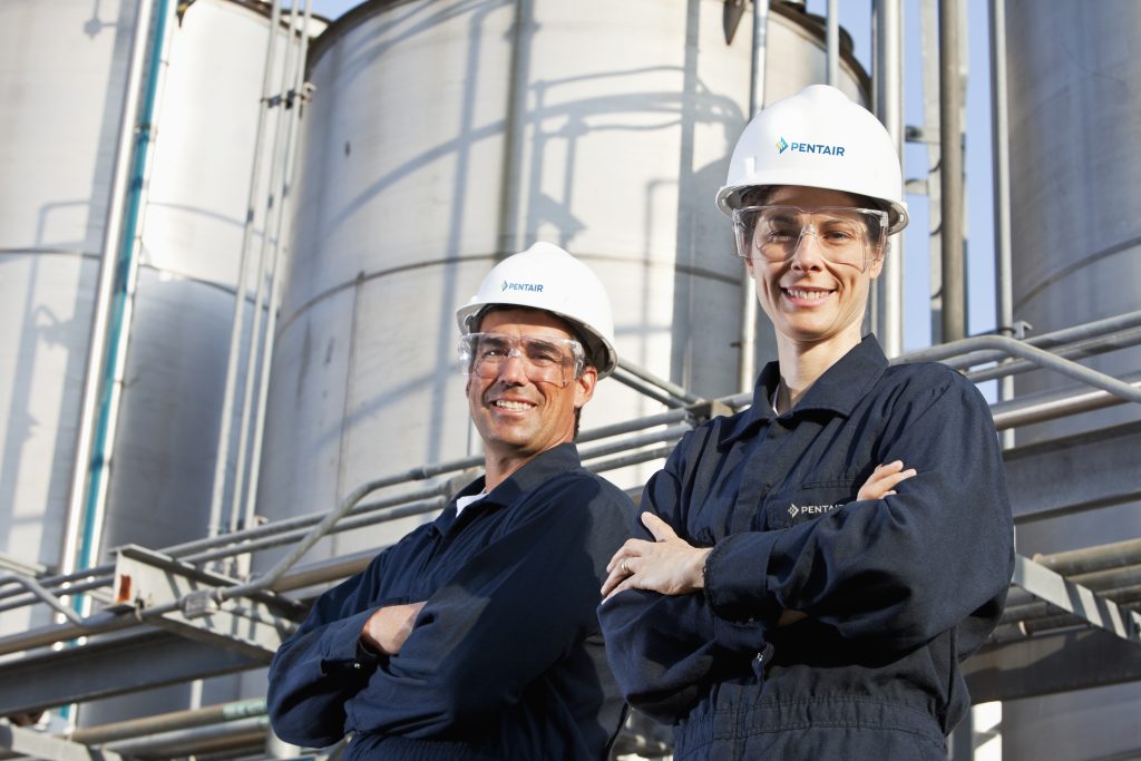 Pentair workers at a chemical manufacturing plant, arms crossed, looking down at the camera and smiling at Pentair GIẢI PHÁP CÔNG NGHIỆP