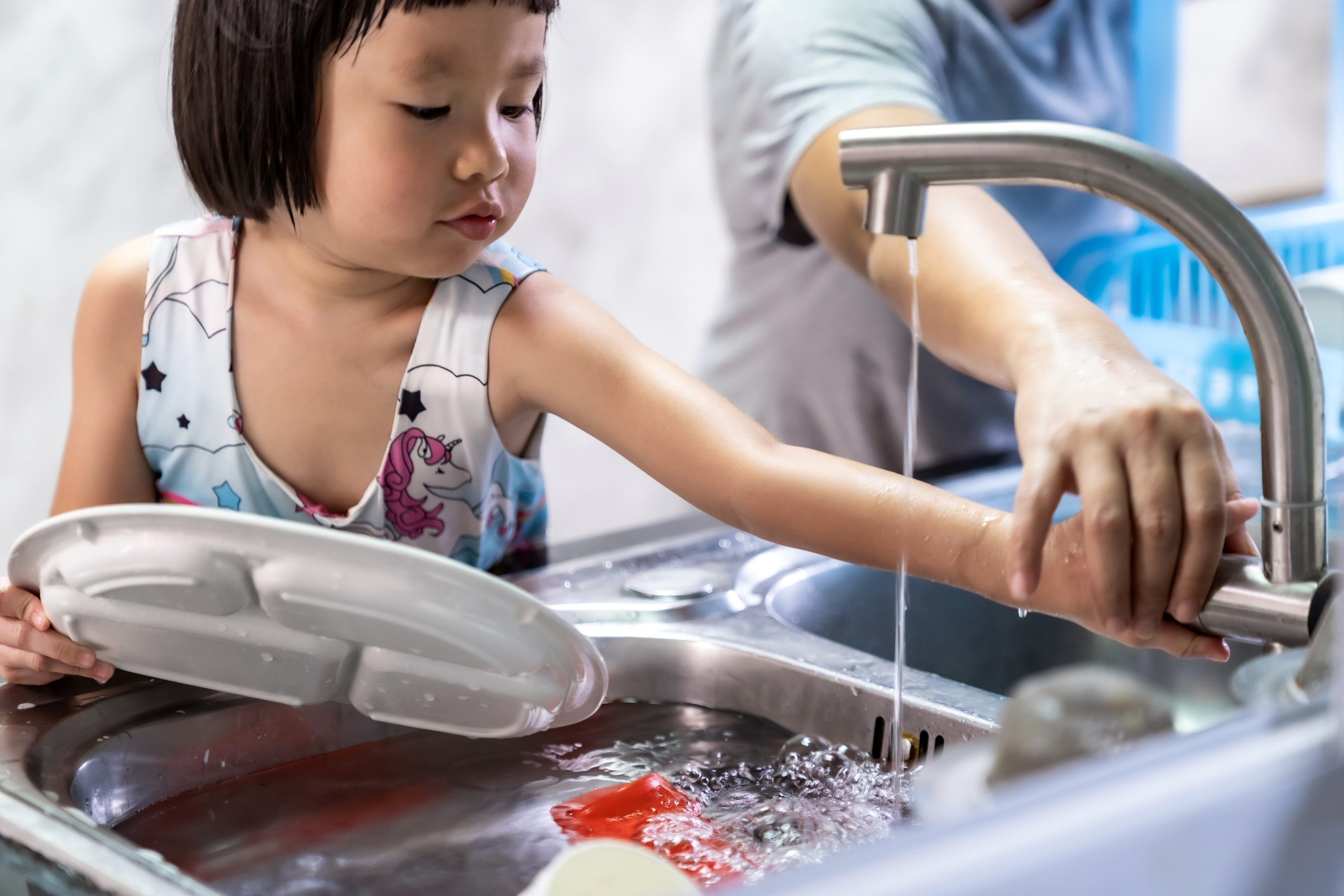 Girl and mom washing dishes powered by Pentair Home Water Filtration System